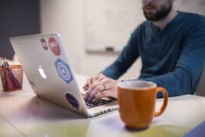Person working on laptop computer with a cup of coffee